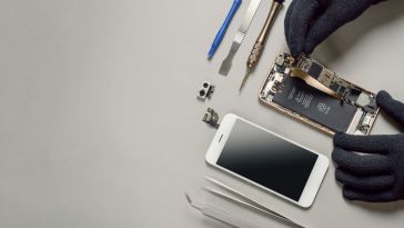 a photo of a disassembled smartphone and a pair of hands working on it.